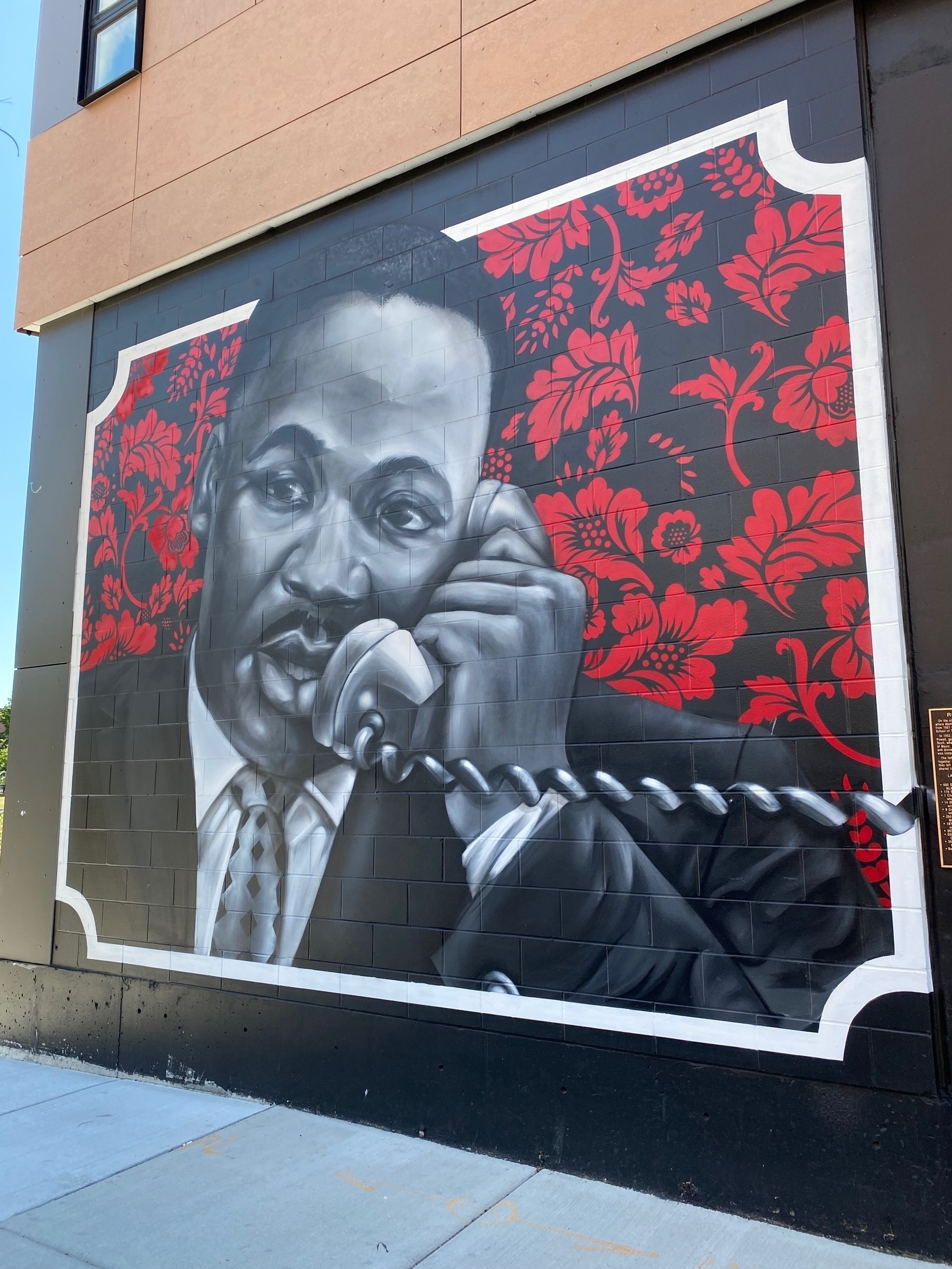 A mural on the side of a building, a black and white drawing of Martin Luther King speaking on a telephone.