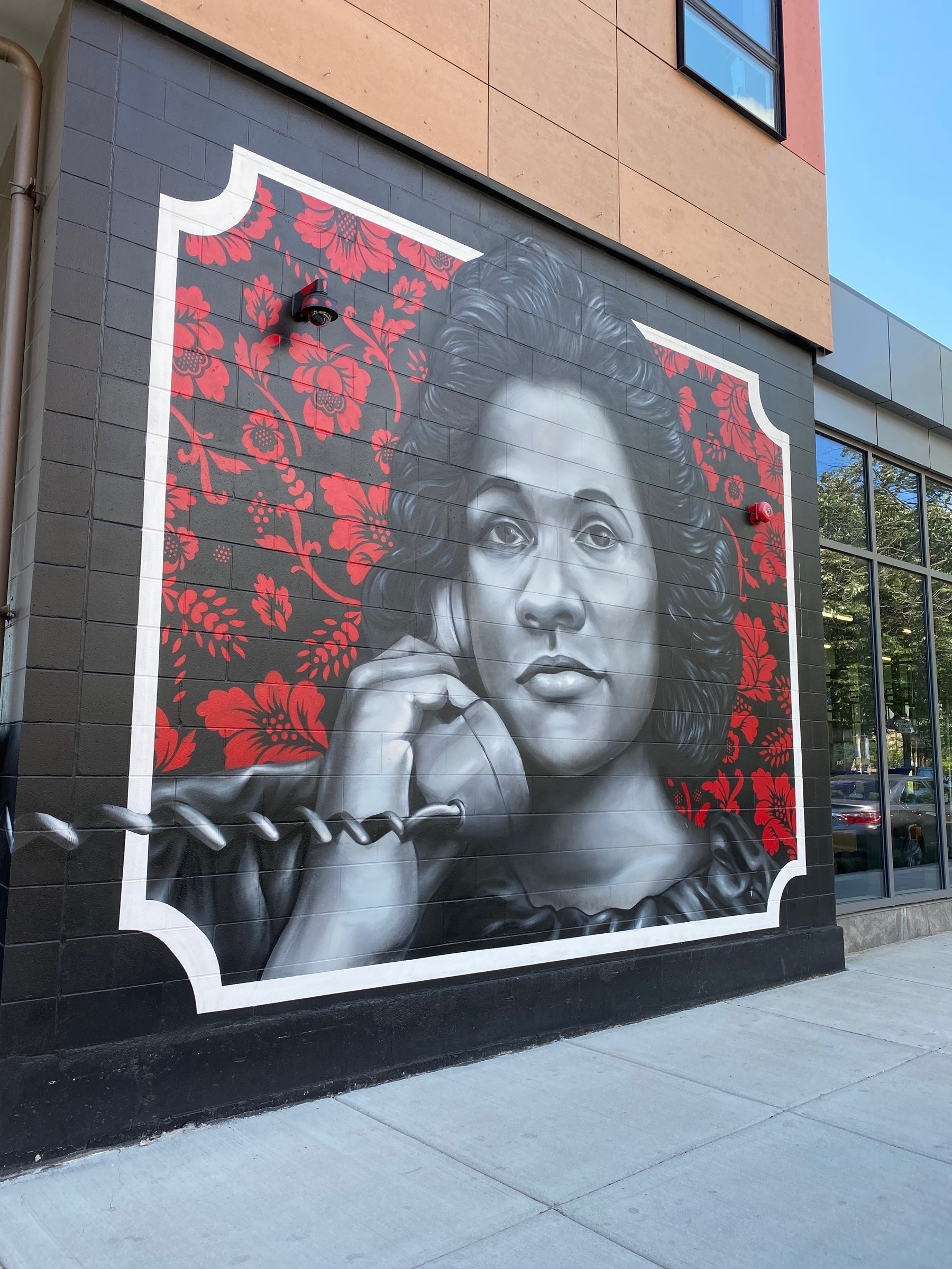 A mural on the side of a building, a black and white drawing of Coretta Scott King listening to a telephone.