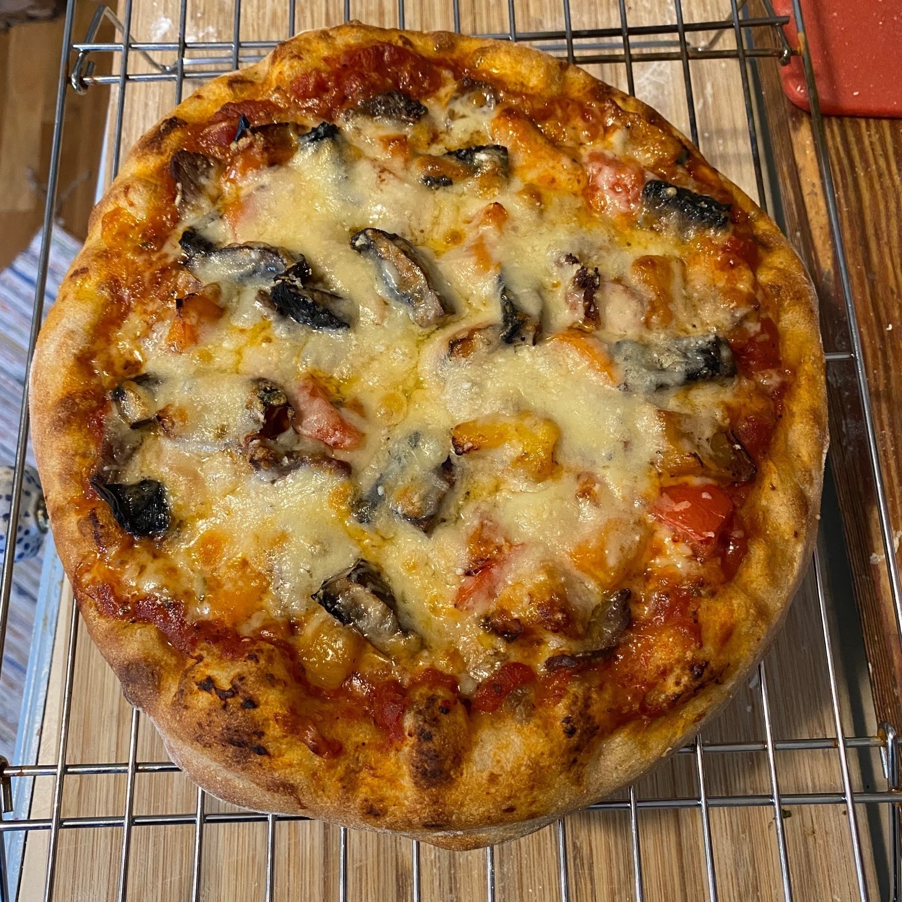 Small pizza with mushrooms on a cooling rack.